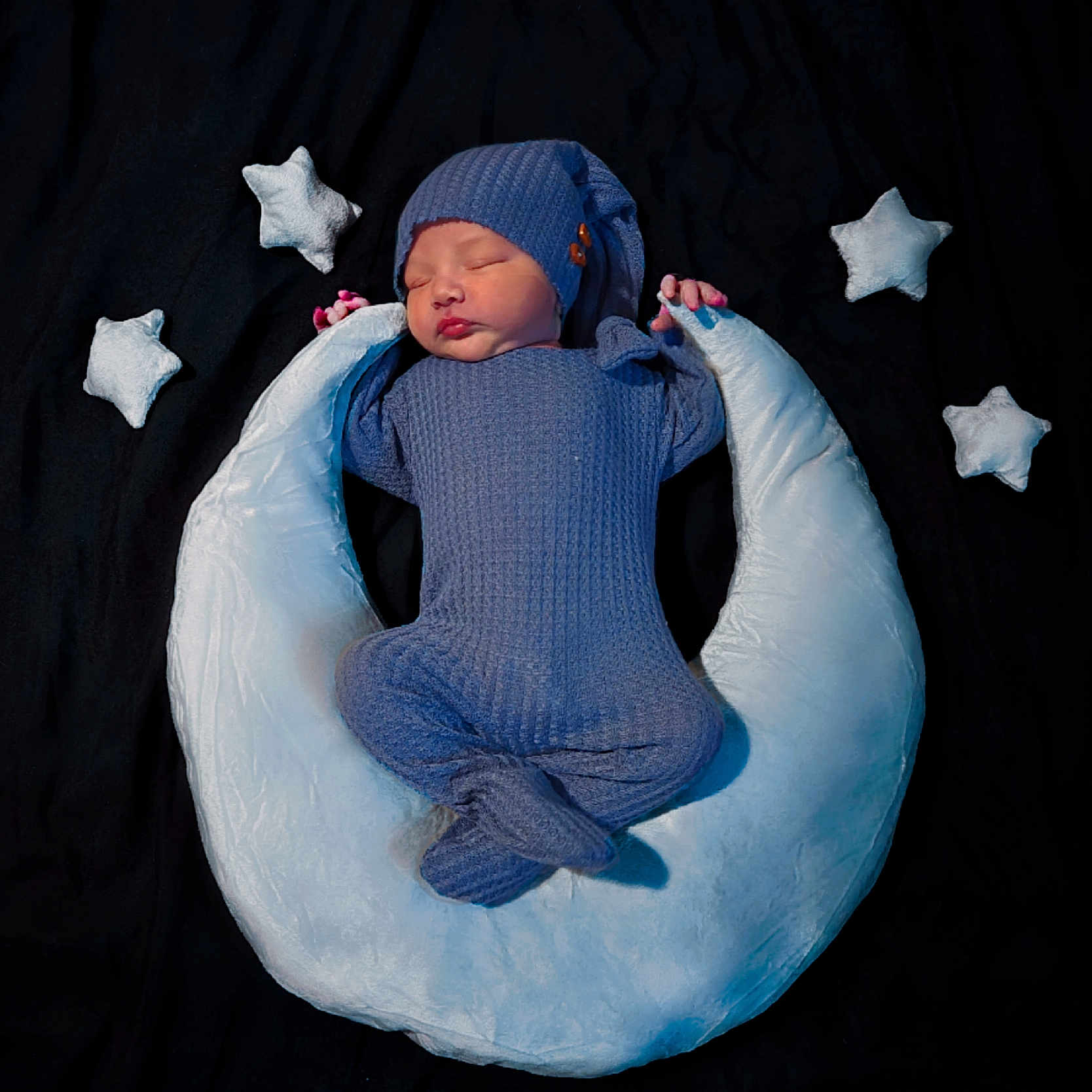 Ezra is registered to the contest to win money with this photo: baby, bedtime, black_background, blue_outfit, child, cozy, crescent_moon, cute, hat, indoor, infant, knitwear, newborn, peaceful, plush_pillow, portrait, resting, sleeping, soft_toys, stars
