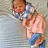 newborn, baby, sleeping, plaid_shirt, peach_pants, blue_socks, striped_blanket, cozy, indoors, cute, infant, resting, peaceful, person, child, portrait, soft_lighting, wooden_floor, casual_clothing, relaxation