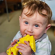Charly a rejoint le concours — aidez-le/la à gagner de superbes lots ! baby, child, blue_eyes, chewing, dinosaur_toy, indoor, cute, hands, short_sleeves, plush_toy, teething, light_brown_hair, portrait, smiling, toddler, toy, white_shirt, young_child, closeup, happy