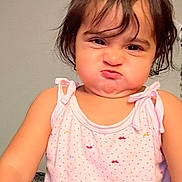Maryam joined the competition — help win amazing prizes! child, toddler, baby, portrait, indoors, pink_outfit, dress, sitting, facial_expression, pouting, puffed_cheeks, brown_hair, shoulder_length_hair, looking_at_camera, closeup, home, wall, ceiling, carpet, humorous