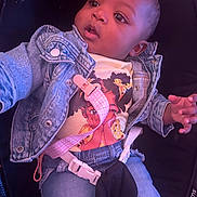Kaiomi joined the competition — help win amazing prizes! baby, child, infant, car_seat, denim_jacket, clothing, shirt, jeans, toy, pacifier_clip, seat_belt, portrait, face, eyes, looking_up, sitting, indoor, purple_lighting, curious, photograph
