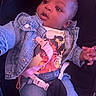 baby, child, infant, car_seat, denim_jacket, clothing, shirt, jeans, toy, pacifier_clip, seat_belt, portrait, face, eyes, looking_up, sitting, indoor, purple_lighting, curious, photograph