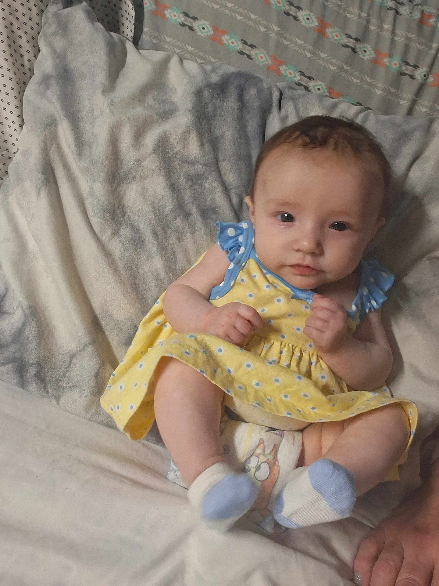 Lilith is registered to the contest to win money with this photo: baby, infant, bed, blanket, diaper, socks, yellow_dress, pillow, patterned_sheet, cute, portrait, indoors, hand, smile, lying_down, bedding, soft_light, blue, newborn, toddler