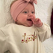 Yliana participe au concours pour gagner de l'argent avec cette photo : baby, infant, headband, pink, bow, sweater, clothing, smile, happy, face, hand, finger, lying_down, blanket, texture, cute, love, cozy, indoor, child