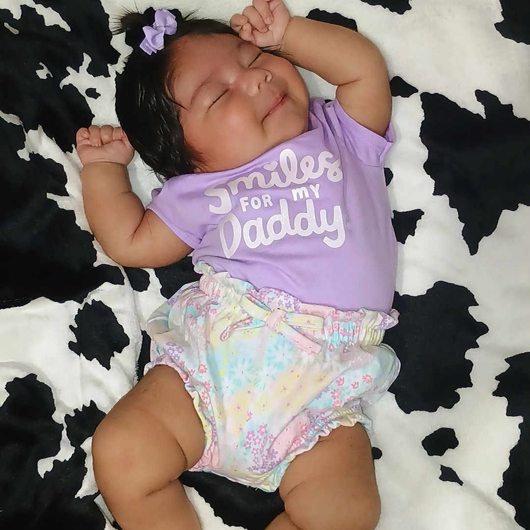 Kai joined the competition — help win amazing prizes! arms, baby, blanket, bow, child, clothing, cow_print, cute, indoors, infant, legs, pattern, peaceful, person, purple_shirt, relaxed, sleeping, smile, soft_texture, toddler