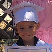 Josiyah joined the competition — help win amazing prizes! baby, baseballcap, cap, clothing, dress, face, graduation, hat, head, people, person