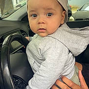 Noah a rejoint le concours — aidez-le/la à gagner de superbes lots ! toddler, child, baby, cap, hoodie, hand, steering_wheel, car_interior, curious, portrait, clothing, seat, driving, vehicle, window, urban, casual, person, cute, indoor