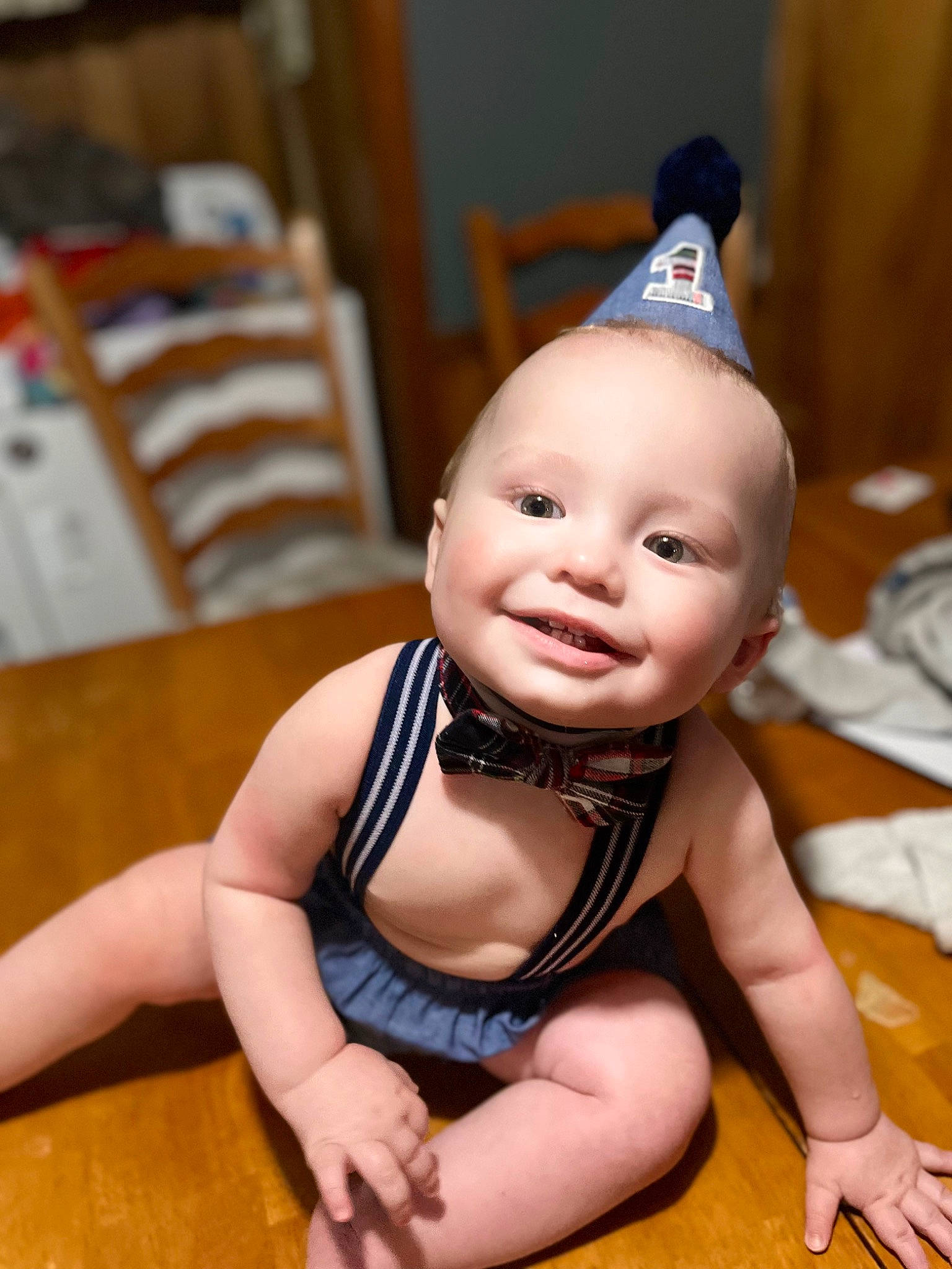 Walter is registered to the contest to win money with this photo: baby, baby_toddler_clothing, cheek, chin, costume_hat, eye, floor, flooring, foot, fun, happy, headgear, human_body, joy, party_hat, party_supply, person, smile, thumb, toddler