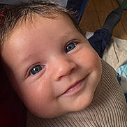 Jayce is registered to the contest to win money with this photo: baby, infant, child, smile, blue_eyes, close_up, portrait, cheeks, dimple, eyelashes, skin, hair, ribbed_clothing, fabric, playpen, hardwood_floor, sock, blanket, indoor, candid