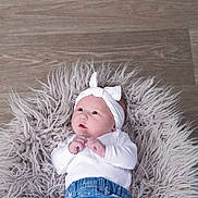 Everly is registered to the contest to win money with this photo: baby, infant, headband, white_clothing, blue_jeans, fluffy_rug, wooden_floor, cute, newborn, portrait, lying_down, indoor, soft_texture, small_hands, curious_look, child, adorable, fashion, clothing, casual