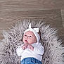 baby, infant, headband, white_clothing, blue_jeans, fluffy_rug, wooden_floor, cute, newborn, portrait, lying_down, indoor, soft_texture, small_hands, curious_look, child, adorable, fashion, clothing, casual