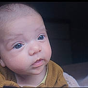 Ellie is registered to the contest to win money with this photo: baby, infant, face, blue_eyes, curious, close_up, portrait, child, young, cozy, clothing, indoors, soft_light, expression, skin, head, person, cute, warm, baby_clothes