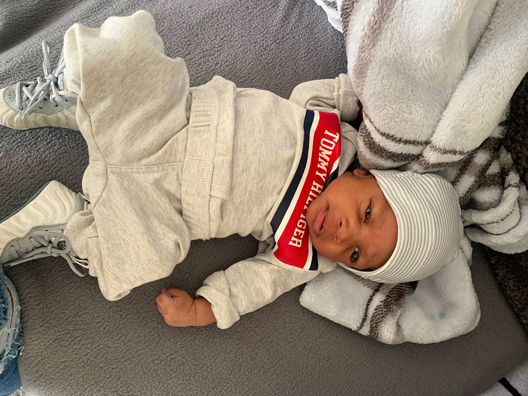 Zayvion is registered to the contest to win money with this photo: baby, baby_products, baby_toddler_clothing, carmine, child, comfort, foot, hand, hat, head, headwear, human_leg, knee, lap, linens, nap, person, sitting, sleeve, sock