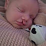 baby, sleeping, blanket, knitted, plush_toy, heart_pattern, closeup, soft_texture, infant, peaceful, cozy, child, portrait, indoor, cute, wrapped, resting, head, face, young