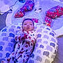 Carmello joined the competition — help win amazing prizes! baby, infant, pajamas, elephant_pattern, pillow, christmas_tree, ornaments, blue_lights, wrapped_presents, floor, holiday, festive, sparkly, tree_skirt, indoor, cute, smiling, relaxing, decoration, cozy