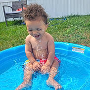 Carmello joined the competition — help win amazing prizes! toddler, child, water, pool, splashing, outdoor, grass, chair, smiling, happy, curly_hair, summer, sunny, bare_chest, playing, blue, plastic_pool, water_droplets, backyard, fun