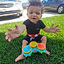 Carmello joined the competition — help win amazing prizes! barefoot, black_clothing, cars, child, clouds, colorful, curly_hair, daylight, drum, grass, hands, happy, outdoor, play, shorts, sitting, sky, smiling, toddler, toy