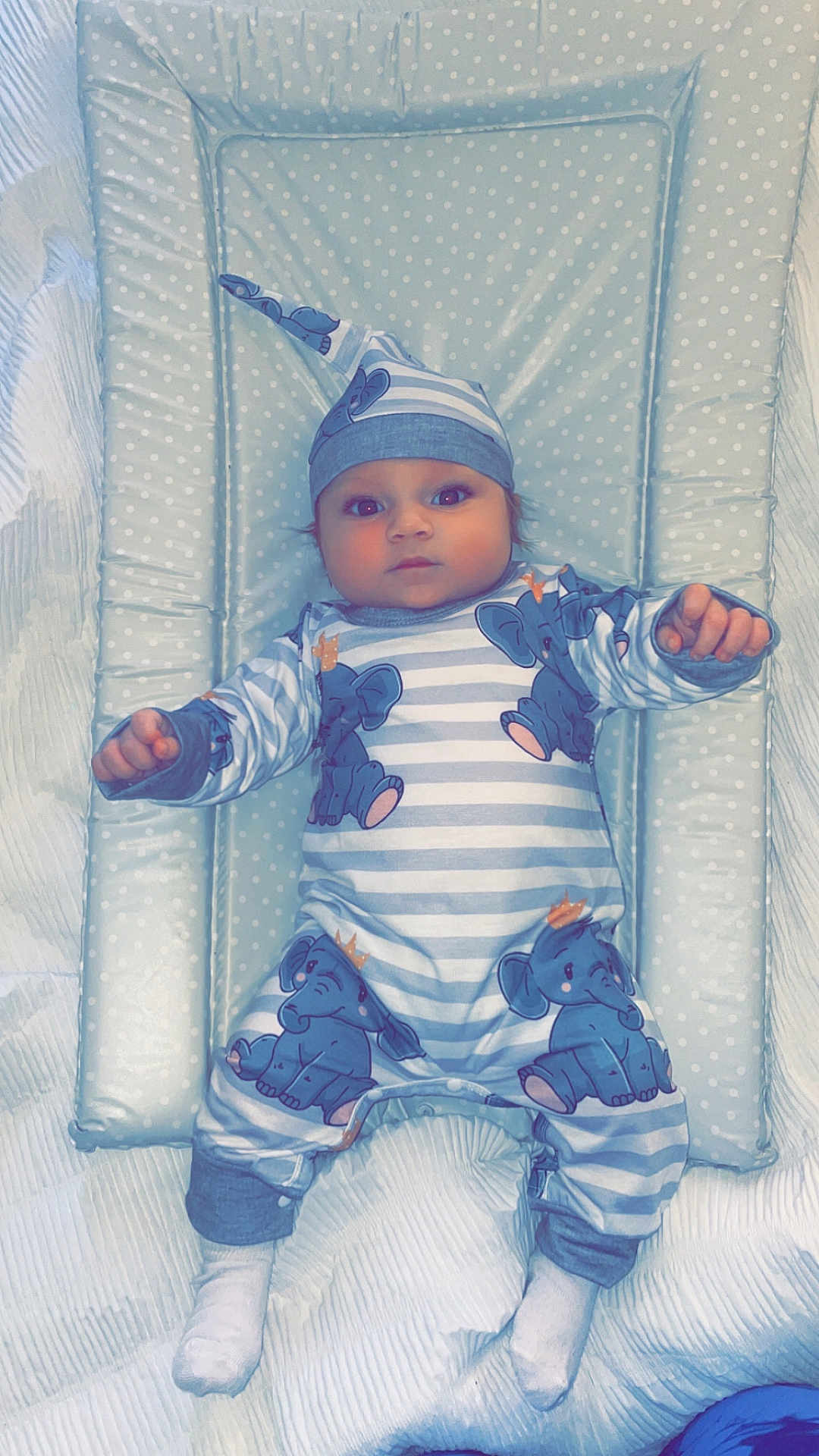 Kody is registered to the contest to win money with this photo: baby, baby_boy, child, cute, elephant_print, hat, indoors, infant, infant_clothing, lying_down, newborn, onesie, padded_mat, polka_dot, portrait, resting, sleepwear, soft_fabric, striped_clothing, white_socks