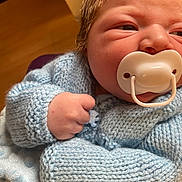Kody is registered to the contest to win money with this photo: baby, newborn, pacifier, blue_sweater, knitted_clothing, infant, close_up, fist, soft_texture, indoor, cute, child, person, skin, hair, warm_clothing, portrait, hand, baby_clothes, sleepy