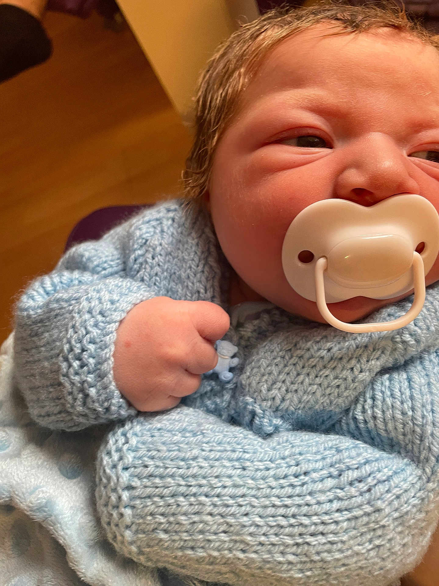 Kody is registered to the contest to win money with this photo: baby, newborn, pacifier, blue_sweater, knitted_clothing, infant, close_up, fist, soft_texture, indoor, cute, child, person, skin, hair, warm_clothing, portrait, hand, baby_clothes, sleepy