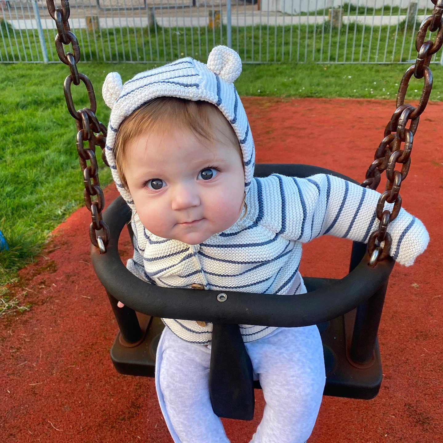 Kody joined the competition — help win amazing prizes! baby, child, swing, playground, hoodie, striped_clothing, cute, infant, outdoor, grass, red_surface, seat, chain, smiling, person, park, casual_wear, young_child, face, blue_eyes
