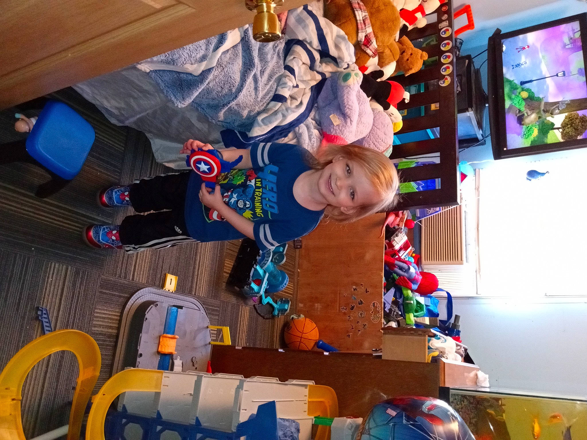 Dennis is registered to the contest to win money with this photo: child, display_device, fictional_character, fun, games, joy, led_backlit_lcd_display, leisure, machine, person, play, recreation, room, smile, space, t_shirt, television, television_set, toddler, toy