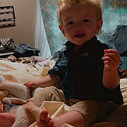 Hank joined the competition — help win amazing prizes! toddler, child, curly_hair, bed, blanket, indoor, clothing, shorts, shirt, person, foot, hand, face, curious, cozy, fabric, pattern, light, room, casual