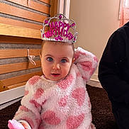 Gabriela participe au concours pour gagner de l'argent avec cette photo : toddler, child, birthday, tiara, pink, fuzzy_clothing, toy, indoor, carpet, wooden_wall, person, cute, portrait, blue_eyes, celebration, baby, happy, sitting, hand, cozy