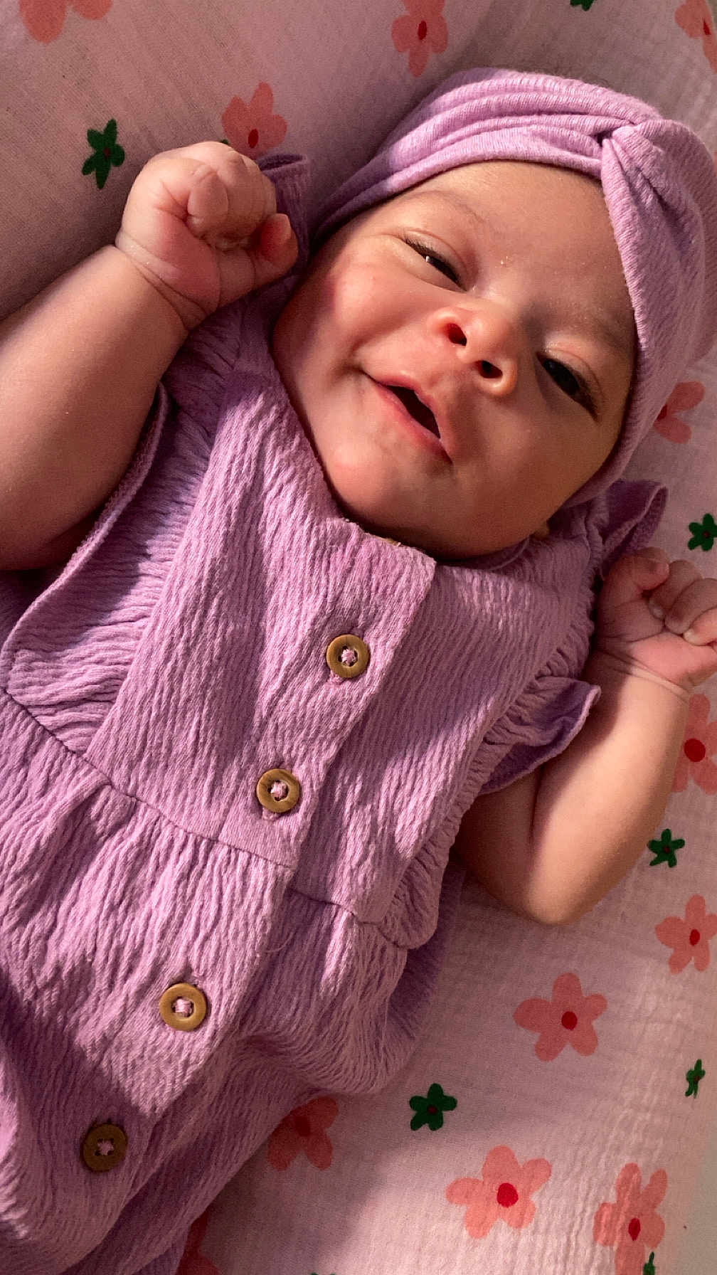 Chehla participe au concours pour gagner de l'argent avec cette photo : baby, infant, smiling, purple_clothing, headwrap, blanket, floral_pattern, cute, portrait, happy, skin, face, child, newborn, lying_down, buttoned_dress, indoors, soft_light, small_hands, peaceful
