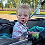 basketball_court, blanket, blue, casual_clothing, child, curly_hair, daytime, expression, face, gray, green, outdoor, park, playground, sippy_cup, stroller, summer, sunlight, toddler, toy