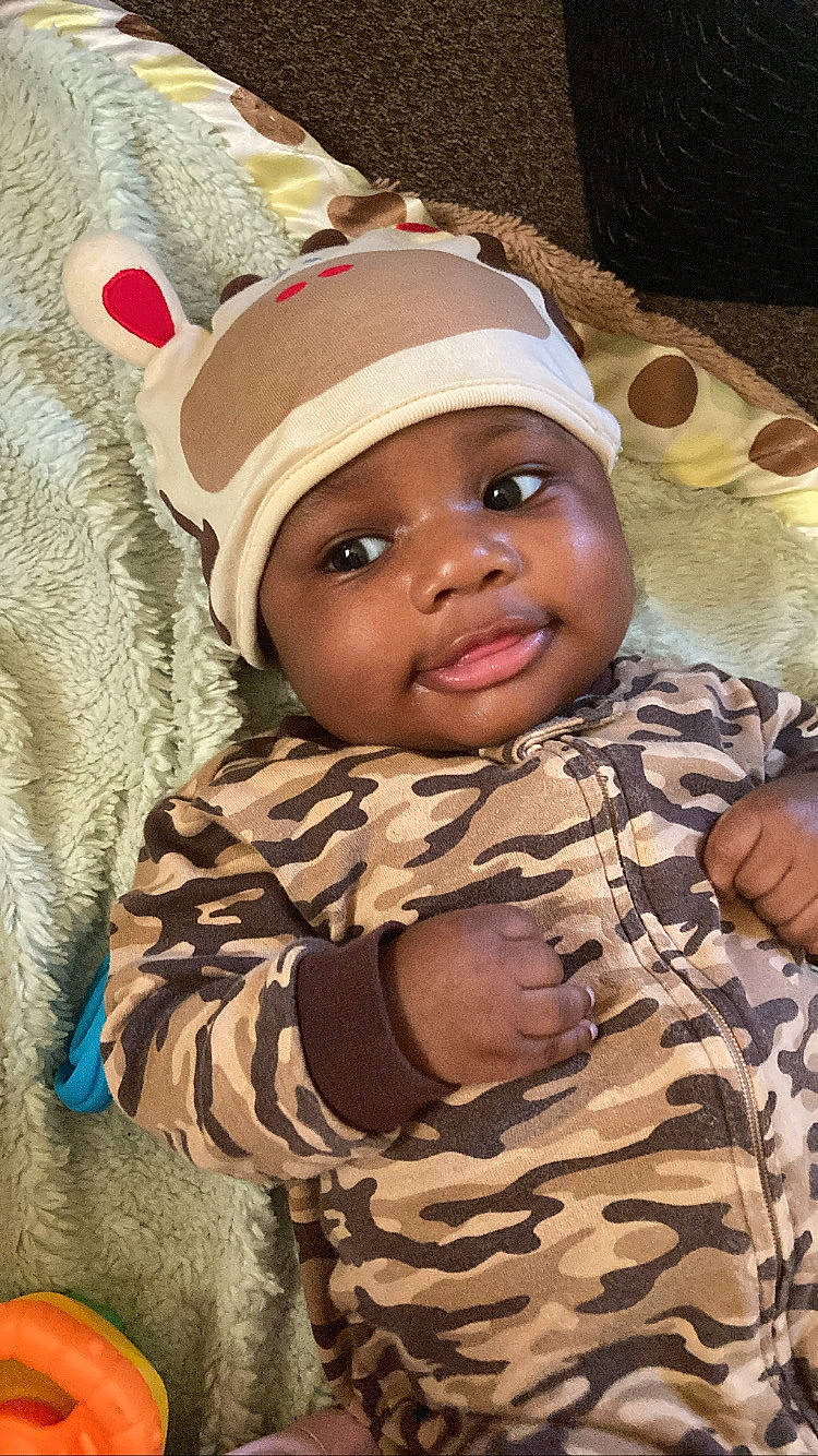 Jamichael joined the competition — help win amazing prizes! baby, cap, cheek, child, eye, fun, happy, headgear, headwear, laugh, linens, military_camouflage, mouth, pattern, person, room, skin, smile, soldier, toddler