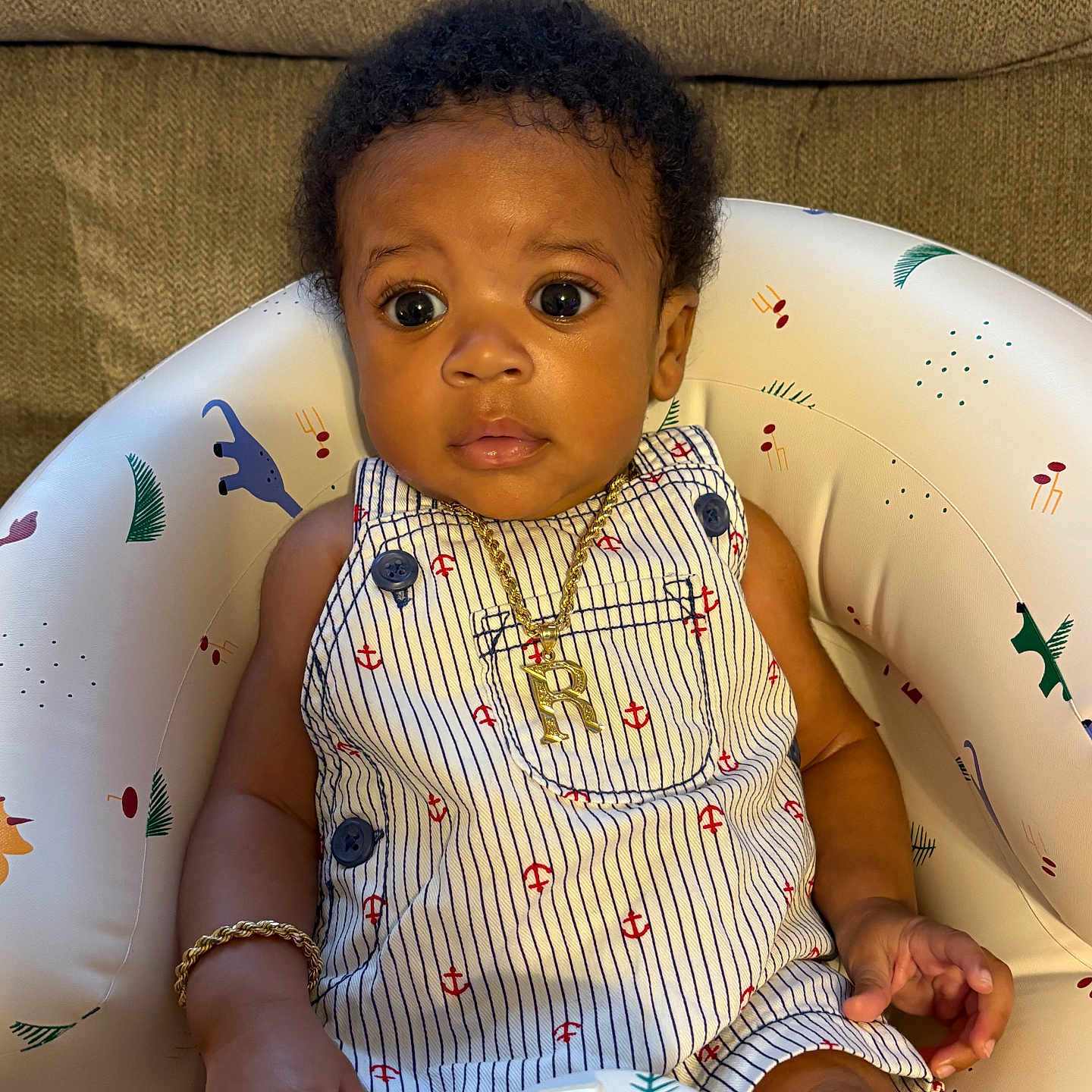 Rasheed is registered to the contest to win money with this photo: accessories, animal_prints, baby, baby_seat, baby_toy, child, closeup, clothing, curly_hair, cute, gold_bracelet, gold_necklace, indoor, infant, person, portrait, romper, sitting, striped_clothing, wide_eyes
