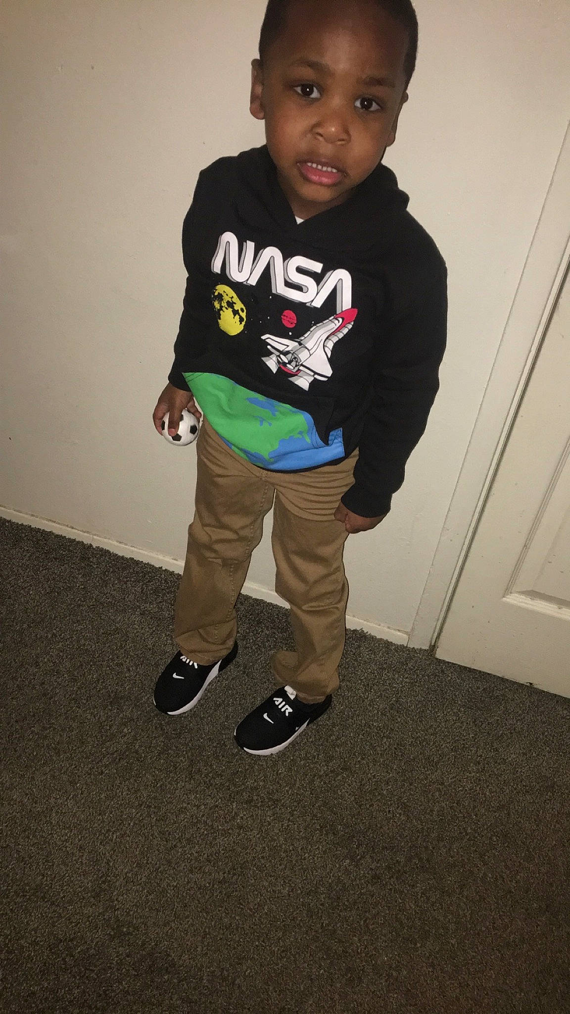 Carter is registered to the contest to win money with this photo: baby_toddler_clothing, cap, child, door, fashion_design, flooring, fun, hair, hoodie, knee, leg, logo, outdoor_shoe, person, sleeve, sportswear, street_fashion, t_shirt, toddler, top