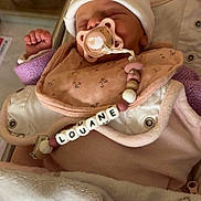 Louane a rejoint le concours — aidez-le/la à gagner de superbes lots ! baby, newborn, pacifier, blanket, hat, sleeping, infant, clothing, bib, beads, person, cute, indoors, resting, soft, warm, comfort, closeup, pink, white