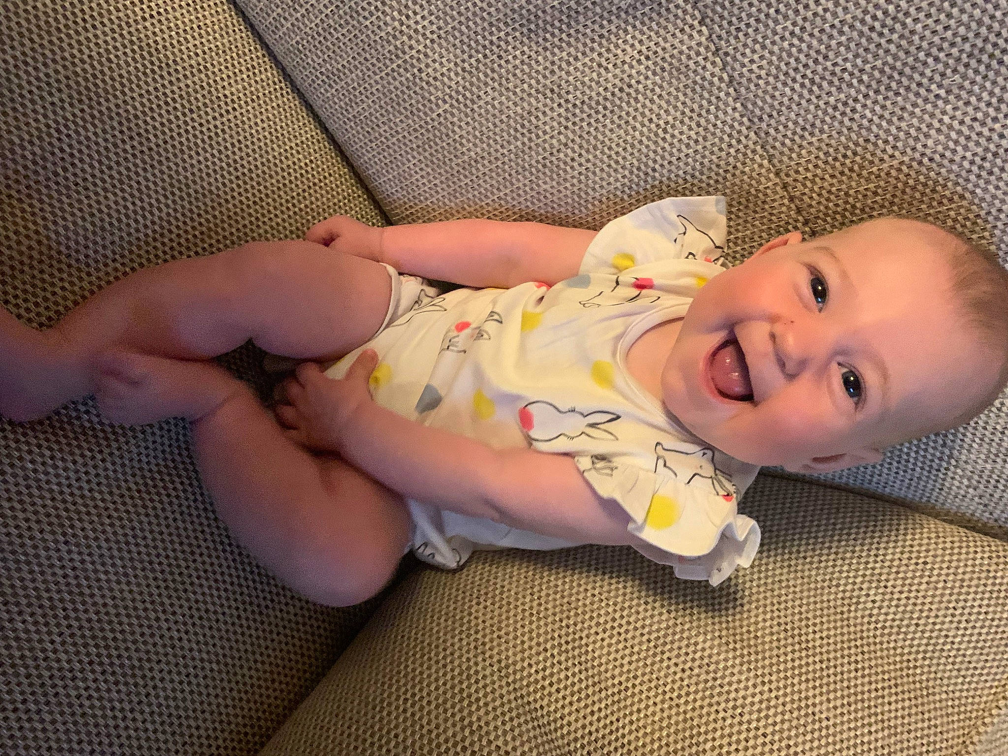 Maddison is registered to the contest to win money with this photo: baby, baby_laughing, baby_products, baby_toddler_clothing, cheek, comfort, eye, face, finger, flooring, head, human_body, lip, mouth, nose, pattern, person, skin, sleeve, smile