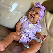 Eleizia a rejoint le concours — aidez-le/la à gagner de superbes lots ! baby, child, smiling, laughing, purple_clothing, headband, bow, couch, indoor, happy, cute, polka_dots, legs, feet, sitting, infant, person, portrait, fun, joy