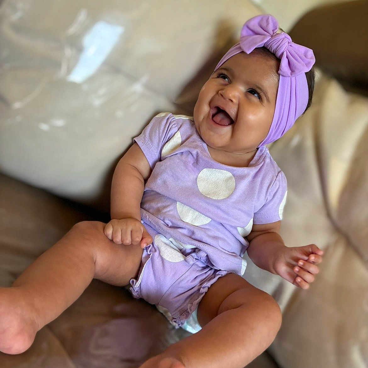Eleizia a rejoint le concours — aidez-le/la à gagner de superbes lots ! baby, bow, child, couch, cute, feet, fun, happy, headband, indoor, infant, joy, laughing, legs, person, polka_dots, portrait, purple_clothing, sitting, smiling