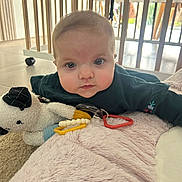 Constance participe au concours pour gagner de l'argent avec cette photo : baby, infant, tummy_time, crib, wooden_slats, playmat, blanket, plush_toy, teether, toy_ring, cheeks, blue_eyes, face, indoor, tile_floor, caster_wheel, clothing, portrait, gaze, soft_texture