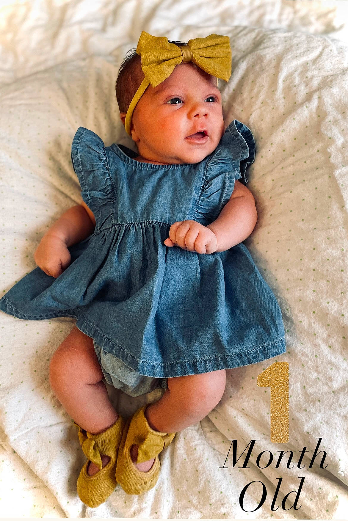 Amelia is registered to the contest to win money with this photo: baby, baby_toddler_clothing, cap, child, doll, dress, eye, face, fashion_accessory, foot, hair_accessory, head, headwear, iris, pattern, person, sandal, sitting, sleeve, toddler