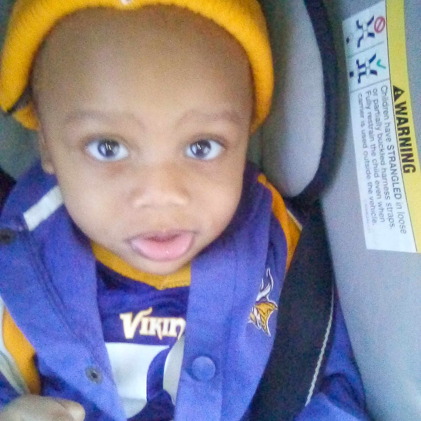 Errion is registered to the contest to win money with this photo: baby, baseballcap, bonnet, cap, car, car_interior, clothing, coat, face, hat, head, jacket, lifejacket, person, photography, portrait, purple, transportation, vehicle, vest