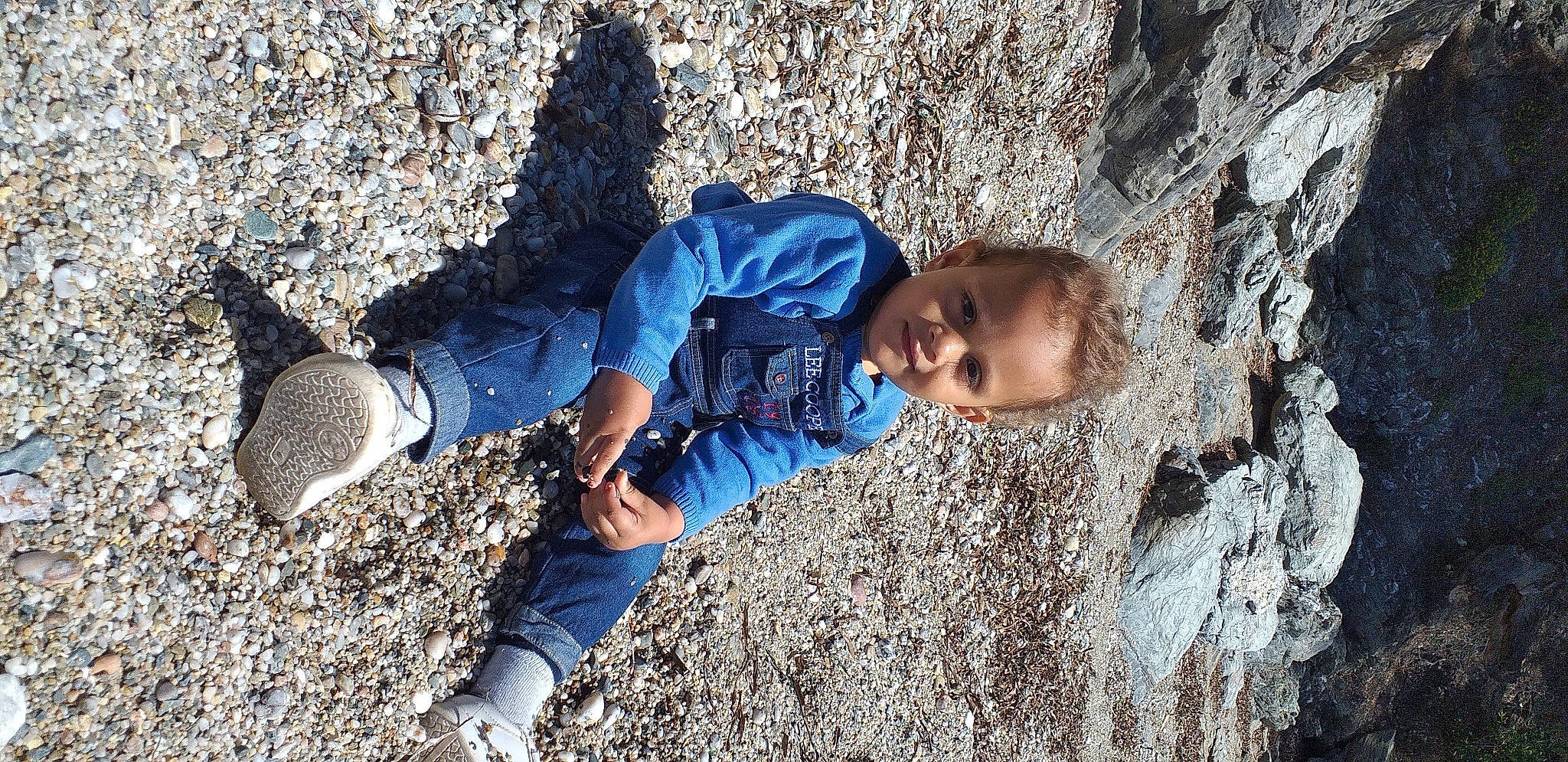 Lucas participe au concours pour gagner de l'argent avec cette photo : child, denim, electric_blue, fun, grass, happy, human_leg, leisure, people_in_nature, person, portrait_photography, rock, shadow, sitting, smile, soil, toddler, tree, vacation, winter