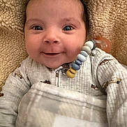 Shiloh is registered to the contest to win money with this photo: baby, smiling, blanket, onesie, pacifier, face, cozy, infant, cute, child, expression, indoors, warm, happy, closeup, person, soft, comfort, head, clothing
