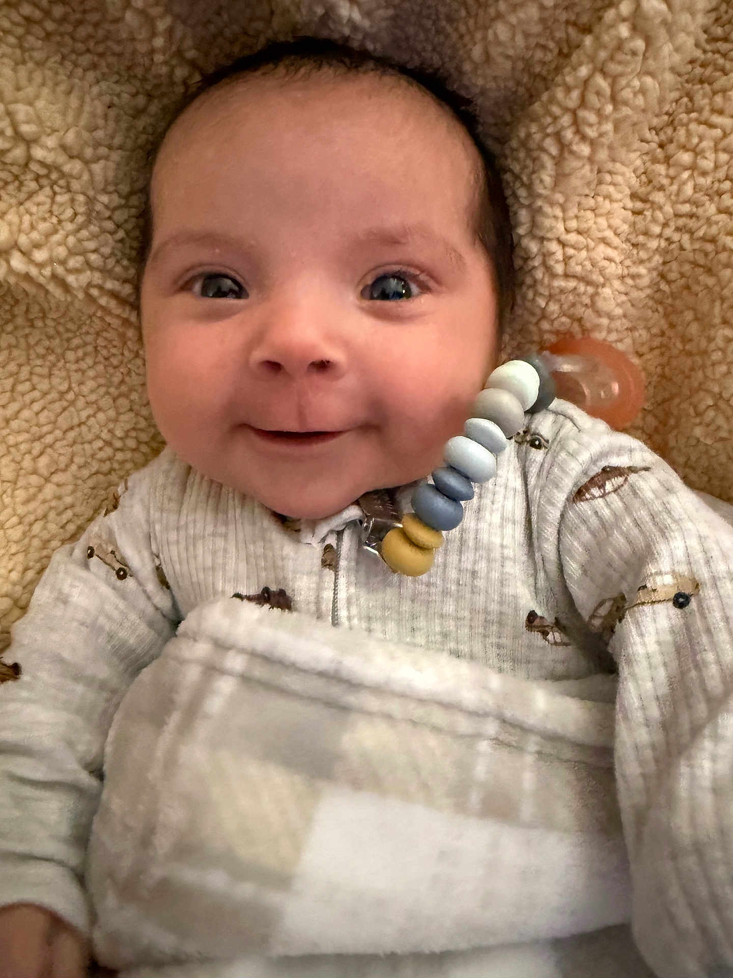 Shiloh is registered to the contest to win money with this photo: baby, smiling, blanket, onesie, pacifier, face, cozy, infant, cute, child, expression, indoors, warm, happy, closeup, person, soft, comfort, head, clothing