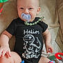 Helios a rejoint le concours — aidez-le/la à gagner de superbes lots ! baby, black_onesie, blanket, blue_toy, child, colorful, cute, dinosaur_print, hand, indoors, infant, leg, pacifier, pink_toy, plush_toy, seated, smiling, soft_texture, star_pattern, toy