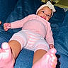 Emonnie is registered to the contest to win money with this photo: baby, child, infant, smiling, portrait, indoor, couch, furniture, pink_clothing, knitwear, headband, bow, blue_background, sitting, lying_down, feet, toes, cozy, home, happy