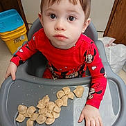Zandar is registered to the contest to win money with this photo: child, cute, expression, eyes, face, floor, food, hand, high_chair, indoor, kitchen, meal_time, pajamas, pasta, plastic_tray, red_clothing, sitting, table, toddler, young_child