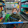 Zandar is registered to the contest to win money with this photo: aisle, baby, bunny_ears, camo_clothing, child, colorful, cute, green_blanket, headwear, indoor, pacifier, person, plush_toys, retail, seatbelt, shopping, shopping_cart, store_shelves, toddler, toy_store