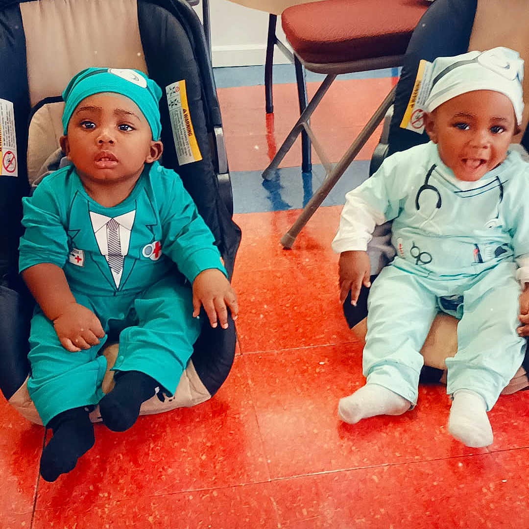 Amarii is registered to the contest to win money with this photo: baby, car_seat, child, clothing, costume, cute, doctor_outfit, floor, happy, headwear, heart_symbol, indoor, infant, playful, portrait, red_floor, seat, serious, smiling, two_children