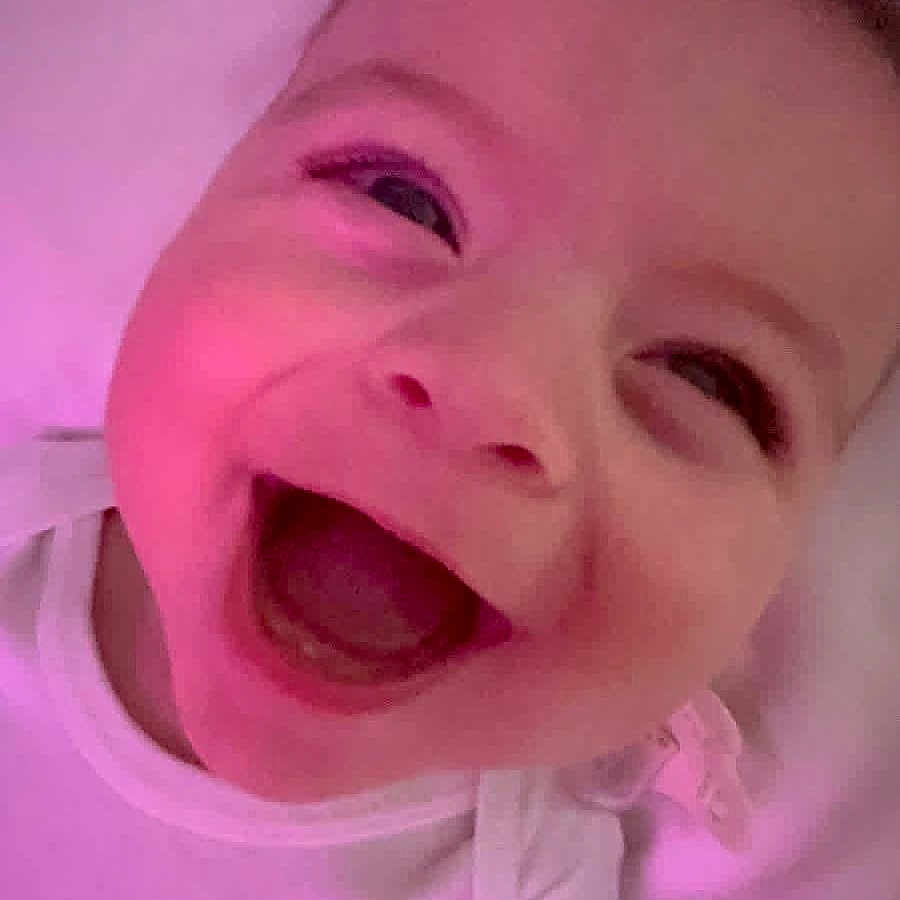 Zehian is registered to the contest to win money with this photo: baby, smiling, laughing, white_clothing, closeup, face, child, infant, joy, happy, pink_light, skin, portrait, cute, expression, one_person, indoors, head, young, sleepwear