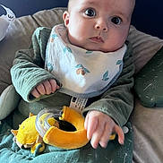 Valentin a rejoint le concours — aidez-le/la à gagner de superbes lots ! baby, bib, child, closeup, comfort, curious, cushion, expression, face, green_clothing, hand, indoor, infant, person, plush_toy, portrait, seated, soft_lighting, wide_eyes, yellow_toy